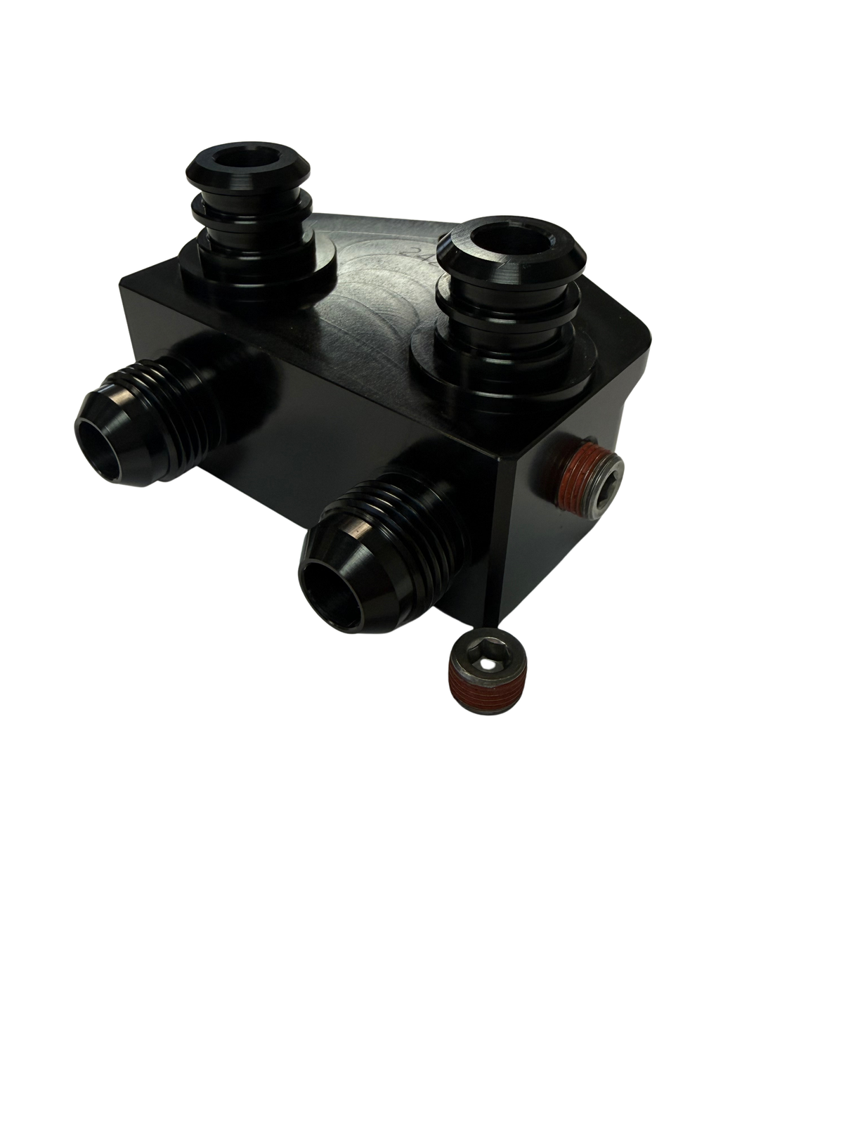 A black metal mechanical component with multiple threaded ports and a small separate cap or fitting placed below it, photographed on a plain white background.