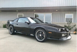 Black 3rd Generation Chevrolet Camaro Z28 parked outside a workshop.