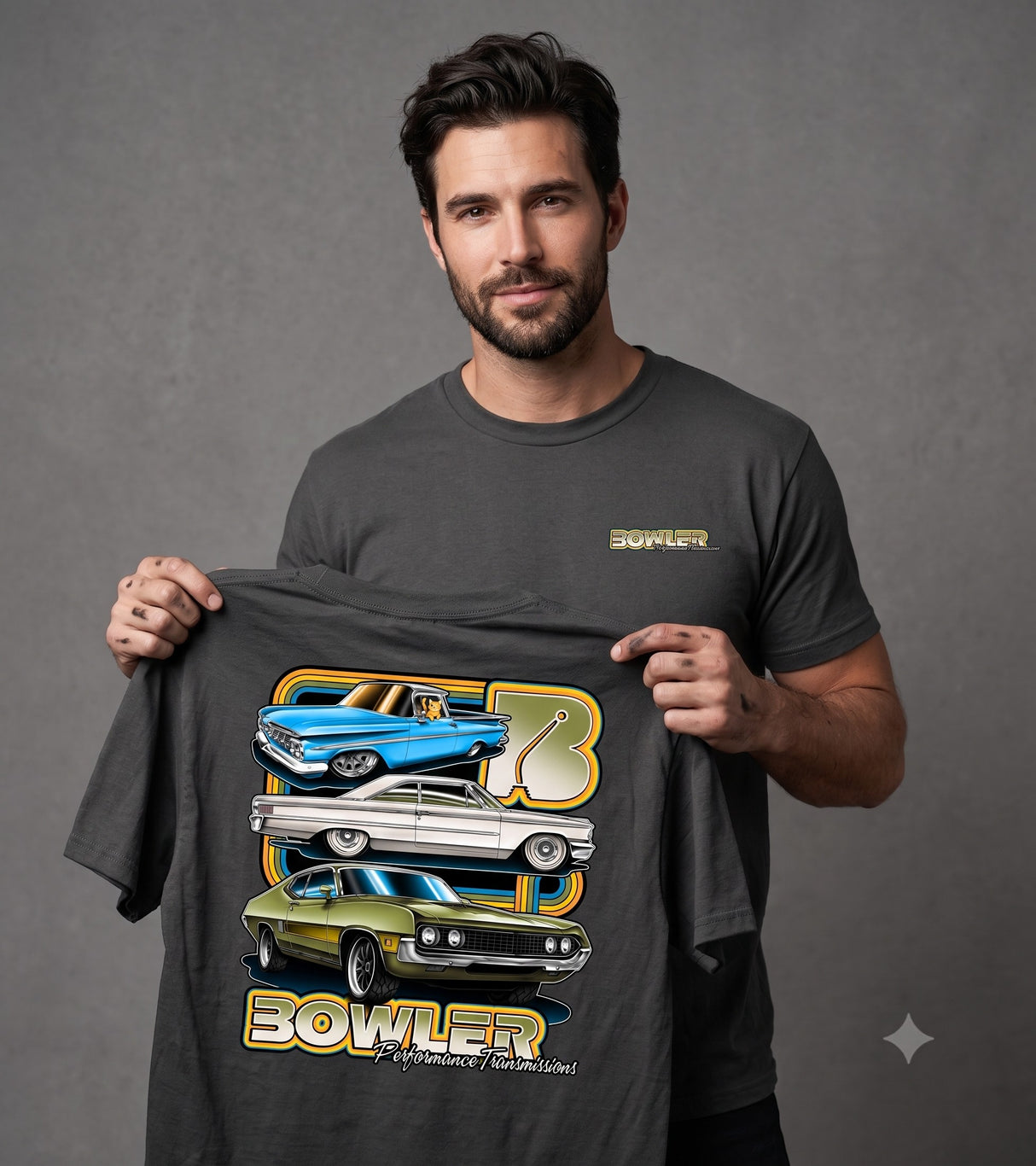 A man wearing a dark gray t-shirt holds up a larger version of the same graphic tee. The graphic features stacked illustrations of classic cars in blue, silver, and green, with the word 'BOWLER' in gold and white.